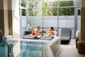 um homem e uma mulher sentados num sofá numa sala com piscina em Hotel Historia & Historante em Veszprém