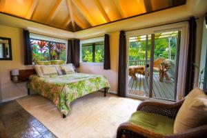 1 dormitorio con 1 cama y balcón con vistas. en The Inn at Kulaniapia Falls, en Hilo