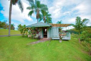 a small house with a porch and palm trees at The Inn at Kulaniapia Falls in Hilo