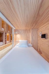 1 cama blanca grande en una habitación con paredes de madera. en Colo Colo Hostel - Single Private Beds, en San Sebastián