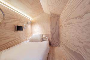 ein kleines Schlafzimmer mit einem weißen Bett und einer Wand in der Unterkunft Colo Colo Hostel - Single Private Beds in San Sebastián