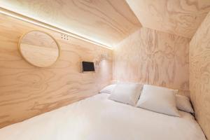 una camera da letto con un letto bianco e uno specchio rotondo di Colo Colo Hostel - Single Private Beds a San Sebastián