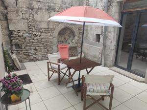 stół i krzesła z parasolem na patio w obiekcie Studio de charme, au calme dans le vieux Chaumont w mieście Chaumont
