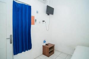 a bathroom with a blue shower curtain and a tv at KoolKost near Margo City Mall in Depok