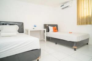 a room with two beds and a table in it at KoolKost near Margo City Mall in Depok