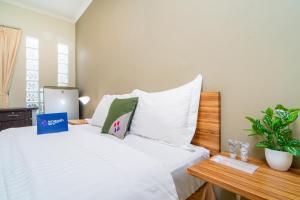 雅加達的住宿－Singgahsini Mampang Prapatan V，一间卧室配有一张带白色床单和一张桌子的床。