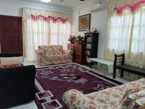 a living room with a couch and a chair and a rug at Homestay YatiMizi (Bungalow Station 18, Ipoh) in Ipoh +3 photos