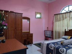 a bedroom with a bed and a dresser and a mirror at Homestay YatiMizi (Bungalow Station 18, Ipoh) in Ipoh