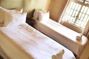 two beds sitting next to a window in a bedroom at Remarkable 3-Bed Cottage in Nyanga in Juliasdale