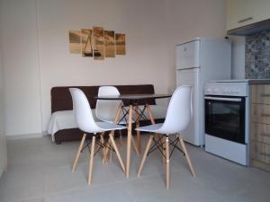 een keuken met een tafel en vier witte stoelen bij Κamares View (Αύρα) in Ayeranós