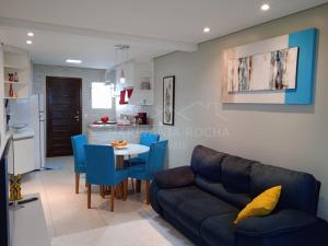 uma sala de estar com um sofá, uma mesa e cadeiras azuis em Apto Aconchegante a 20 mts do Mar e Pertinho do Centro em Matinhos