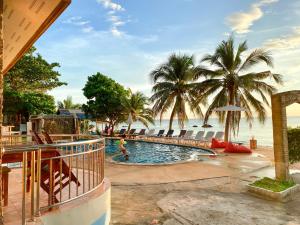 a swimming pool next to a beach with palm trees at Lanta Paradise Beach Resort in Ko Lanta