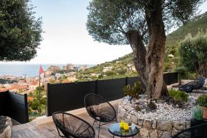 eine Terrasse mit Tischen, Stühlen und einem Baum in der Unterkunft Le petit jardin exotique in Beausoleil