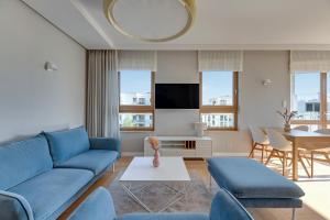uma sala de estar com um sofá azul e uma mesa em Downtown Apartments Seaside Mila Baltica - Sauna, Gym & Parking em Gdansk