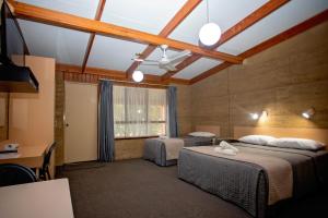 a room with two beds and a desk and a window at Hopetoun Motel & Chalet Village in Hopetoun