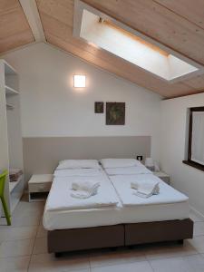 a bedroom with a bed with white sheets and wooden ceilings at La Corte Room & Relax in Rovereto