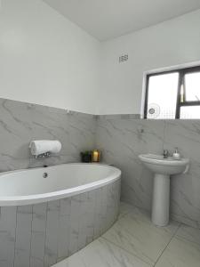uma casa de banho branca com uma banheira e um lavatório em Amour de Soeurs em Norton