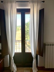 a window with white curtains and a door with a balcony at Agriturismo San Pietro in Gangi