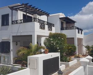 Cette maison blanche dispose de portes noires et d'un balcon. dans l'établissement Casa Sol y Playa, à Playa Honda