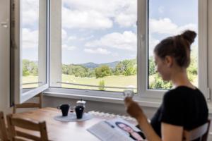 a woman sitting at a table in front of a window at Apartman JakoDoma vlastní parkování u domu ZDARMA in Česká Lípa +25 photos
