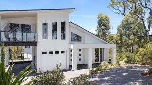 a white house with a balcony on a driveway at Seascape Retreat - Magnificent 5 Bedroom Home in Nelson Bay