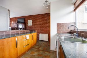 a kitchen with a sink and a brick wall at Head-on-Beds -Dagenham Larger Groups with Free Parking in Dagenham