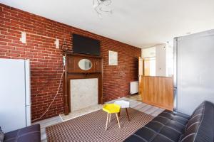 a living room with a brick wall and a yellow stool at Head-on-Beds -Dagenham Larger Groups with Free Parking in Dagenham