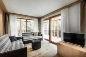 a living room with a couch and a flat screen tv at Chalet Martina Apartments in San Vigilio Di Marebbe