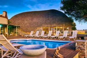 ein rundes Gebäude mit Stühlen und einem Pool in der Unterkunft We Kebi Safari Lodge in Sesriem