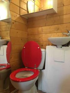 La salle de bains est pourvue de toilettes rouges et d'un lavabo. dans l'établissement Chalet indépendant, à Marseille