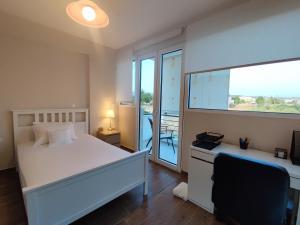 a bedroom with a white bed and a balcony at The Bright House a two-storey maisonette in Loutraki in Loutraki