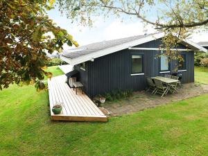 een zwart huis met een houten terras in de tuin bij 6 person holiday home in Ebberup in Helnæs By