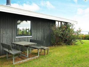 uma mesa de piquenique e duas cadeiras ao lado de um edifício em 6 person holiday home in Ebberup em Helnæs By