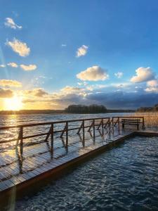 a dock on a body of water with the sun setting at ArtHouse Pelnik in Łukta
