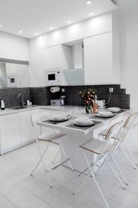 a white kitchen with a white table and chairs at GARDENIA SUPERIOR apartament 33 in Dziwnów