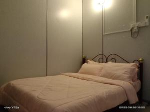 Schlafzimmer mit einem Bett mit weißer Bettwäsche und Kissen in der Unterkunft Rizqy Homestay di Jitra in Jitra