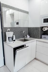 a white kitchen with a sink and a microwave at GARDENIA SUPERIOR apartament 33 in Dziwnów