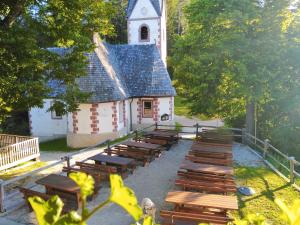 un grupo de bancos de madera frente a una iglesia en koča na pikovem, en Črna na Koroškem