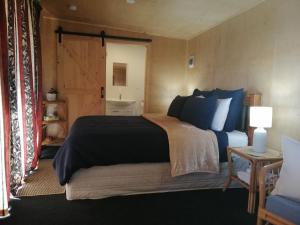 a bedroom with a large bed and a bathroom at Glenwood Akaroa Bush Retreat - Totara Hut in Akaroa