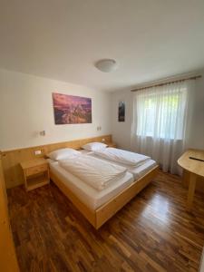 a bedroom with two beds and a table and a window at Amalia Apartment in Santa Cristina Gherdëina