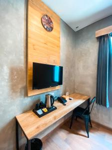 a room with a wooden table with a tv on a wall at Hotel Summerville in Majalengka