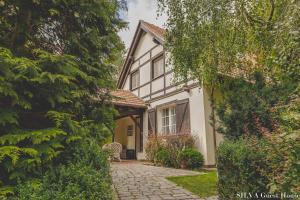 una casa con una pasarela de piedra delante de ella en SILVA Guest House - dom wczasowy, tenis, basen, balia i sauna, en Borsk