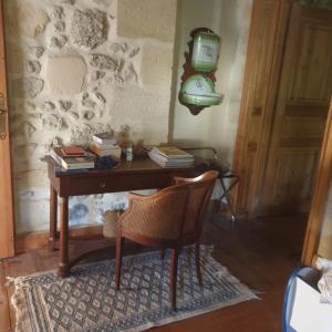 einen Schreibtisch mit Büchern und einem Stuhl in einem Zimmer in der Unterkunft Les Logis de Lestiac in Lestiac-sur-Garonne