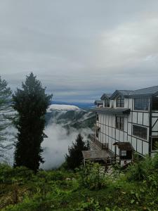 een huis op een heuvel met uitzicht op de wolken bij Sugar Cube Retreat in Shimla