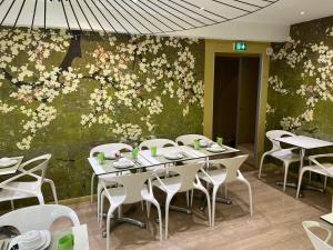 uma sala de jantar com mesas e cadeiras e uma parede com flores em 55 Hôtel Montparnasse em Paris
