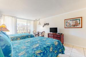 a bedroom with two beds and a desk with a television at Islander on the Beach 370 in Kapaa