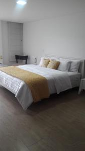 a bedroom with a large bed with white sheets and pillows at Confortable, moderno y hermoso departamento. in Quito