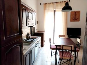 a kitchen with a stove and a table with chairs at Appartamento Porto Marina VA1 in Licata