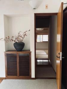 a hallway with a vase on a wooden cabinet with a door at 地中海の家 in Futo