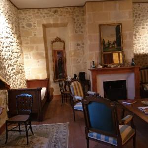 Les Logis de Lestiac في Lestiac-sur-Garonne: غرفة معيشة مع كراسي ومدفأة